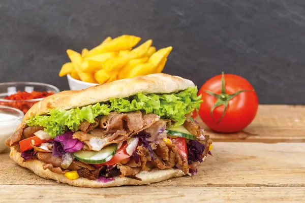 Photo sandwich Kebab sue planche de bois avec frites, sauce et tomate